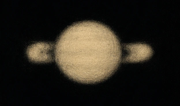 Blurry telescopic view of Saturn showing the historic "ears" appearance recorded by Galileo in 1610.