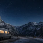 Camper van at a snowy mountain campsite under a starry winter sky.