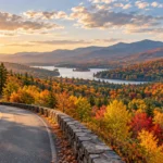 Peak fall foliage covering a mountain valley in red, orange, yellow, and green autumn colors.