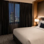 Quiet modern hotel room with blackout curtains and a neatly made bed at night.