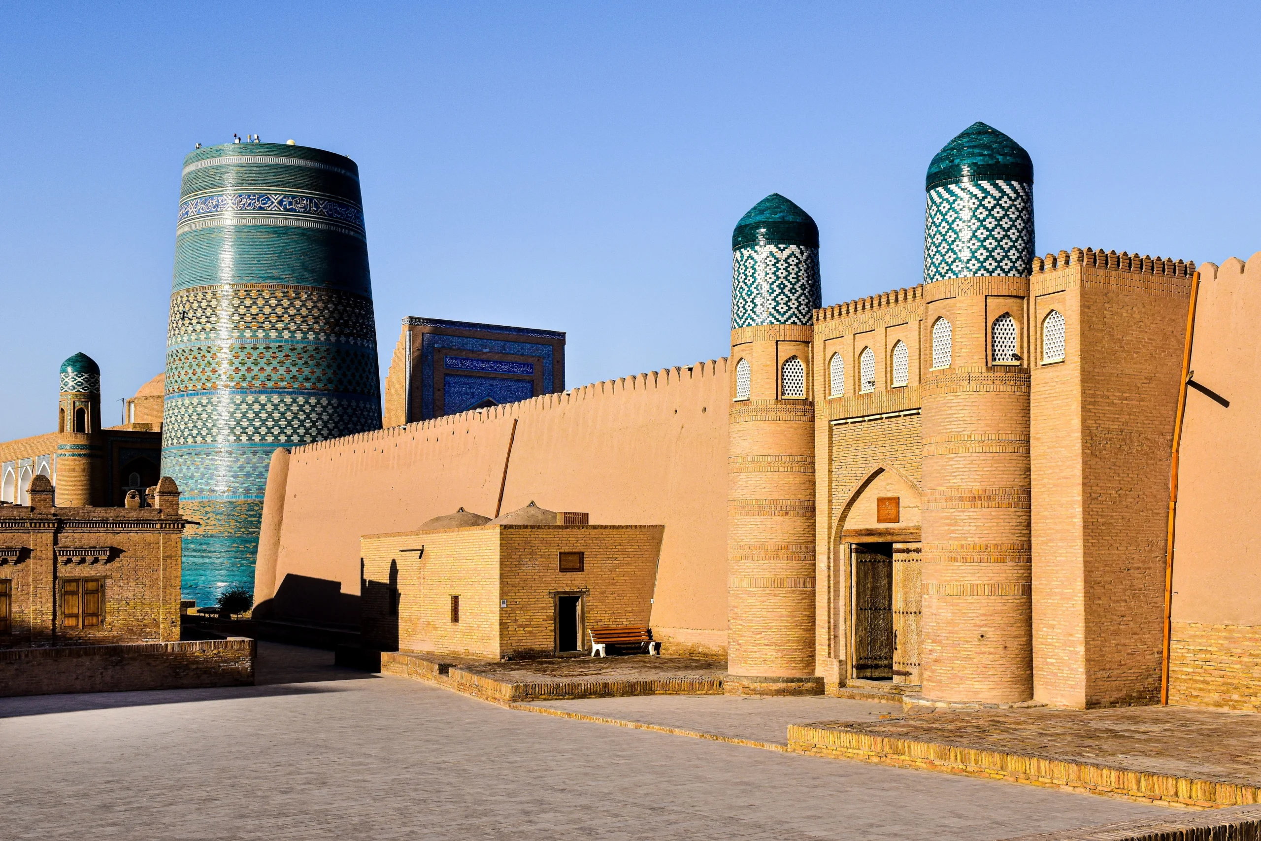 The earthen city walls and unfinished blue-tiled Kalta Minor minaret of Ichan Kala in Khiva, Uzbekistan.