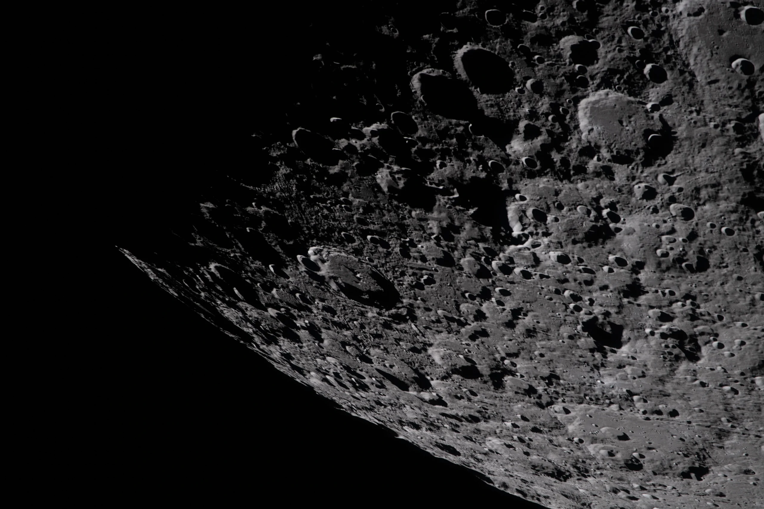 Oblique view of the Moon's cratered surface taken by NASA, showing stark low-angle sunlight and deep black shadows across the lunar terrain.