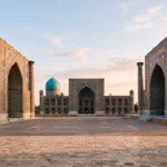 Wide-angle documentary photograph of Registan Square's tiled madrasahs in Samarkand, Uzbekistan, under early morning sunlight.